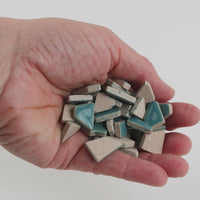Video of Flip ceramic puzzle pieces in mint green, opaque glazed porcelain, 4–20 mm, held in a hand and poured out to show their shapes and finish